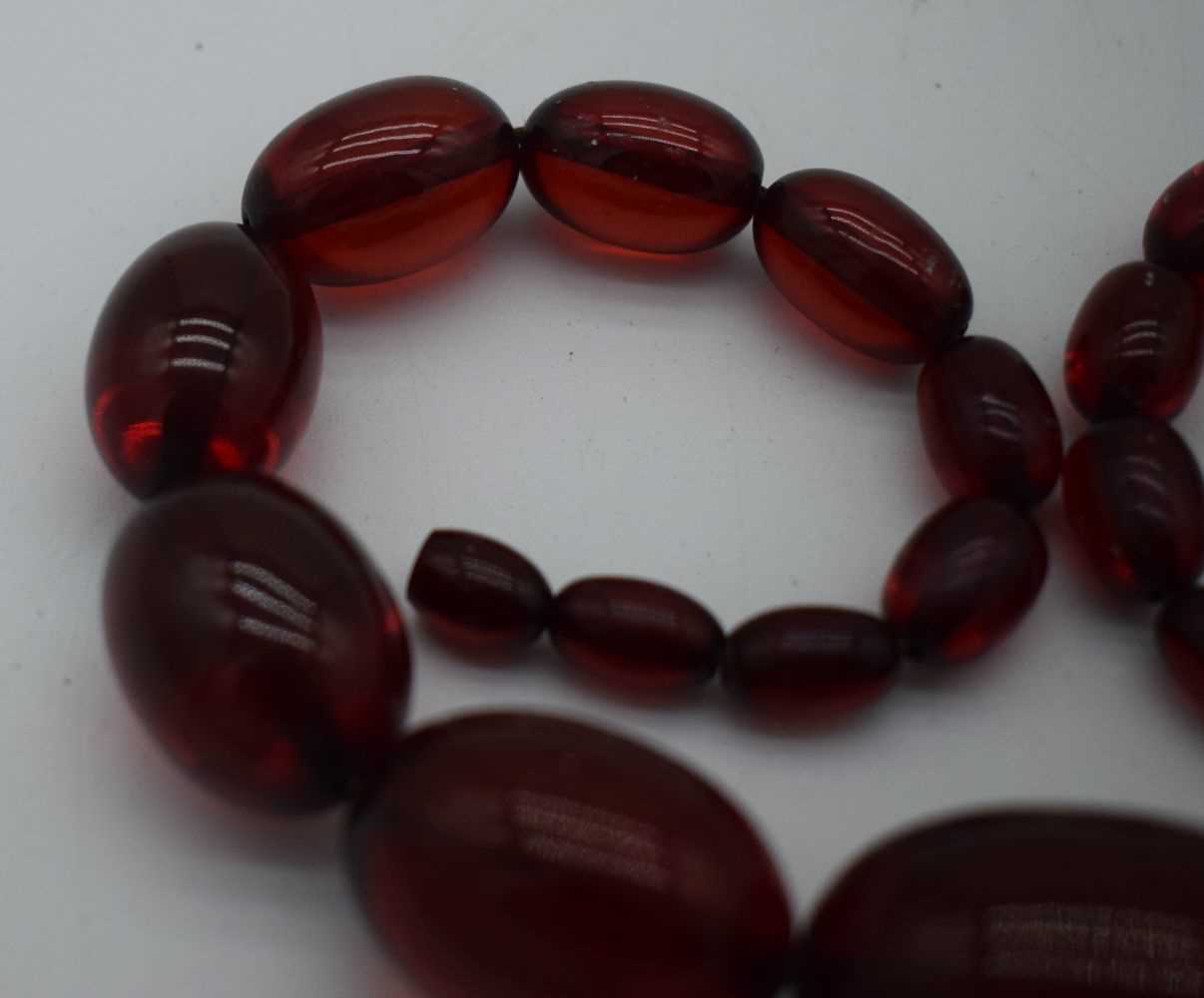 A LARGE CHERRY AMBER TYPE NECKLACE. 77 grams. 45cm long, largest bead 3.5 cm x 2.5 cm. - Image 2 of 3