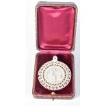 A Mother of Pearl Pierced Pendant depicting a Religious Scene in a fitted case. 5 cm diameter