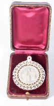 A Mother of Pearl Pierced Pendant depicting a Religious Scene in a fitted case. 5 cm diameter