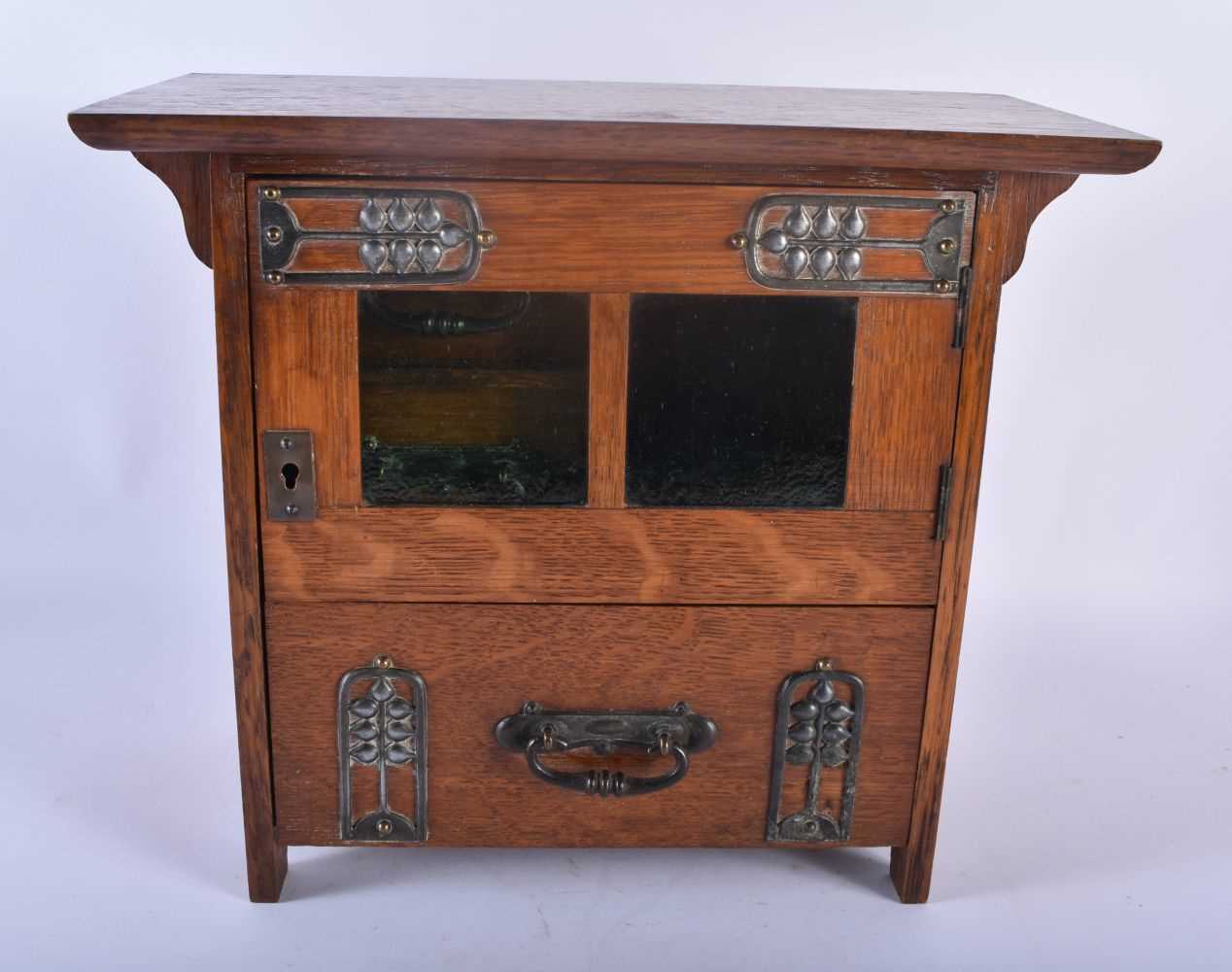 AN ART NOUVEAU OAK SMOKERS CABINET with stylised brass strapwork. 30cm x 28 cm.