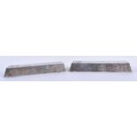 A PAIR OF CHINESE WHITE METAL INGOTS possibly silver scroll weights. 489 grams. 10 cm x 3 cm.