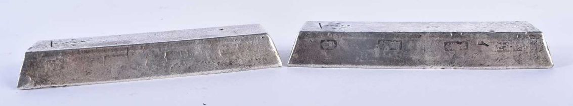 A PAIR OF CHINESE WHITE METAL INGOTS possibly silver scroll weights. 489 grams. 10 cm x 3 cm.