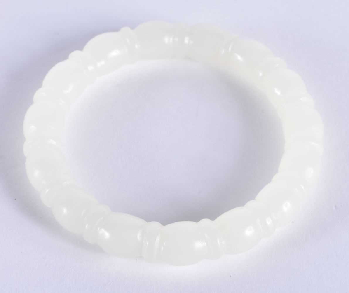 A CHINESE CARVED WHITE JADE RIBBED BANGLE 20th Century. 45.3 grams. 6 cm diameter.