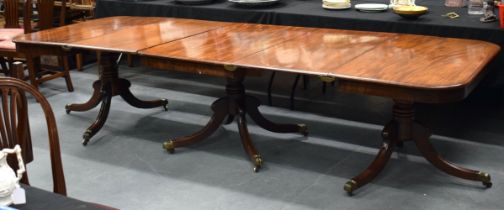 A FINE LARGE REGENCY CARVED MAHOGANY DINING TABLE with bronze capped supports, and two drop in