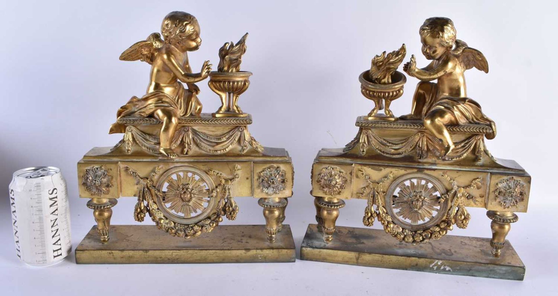 A PAIR OF EARLY 19TH CENTURY FRENCH ORMOLU FIRESIDE COMPANIONS formed as putti beside flaming vases,