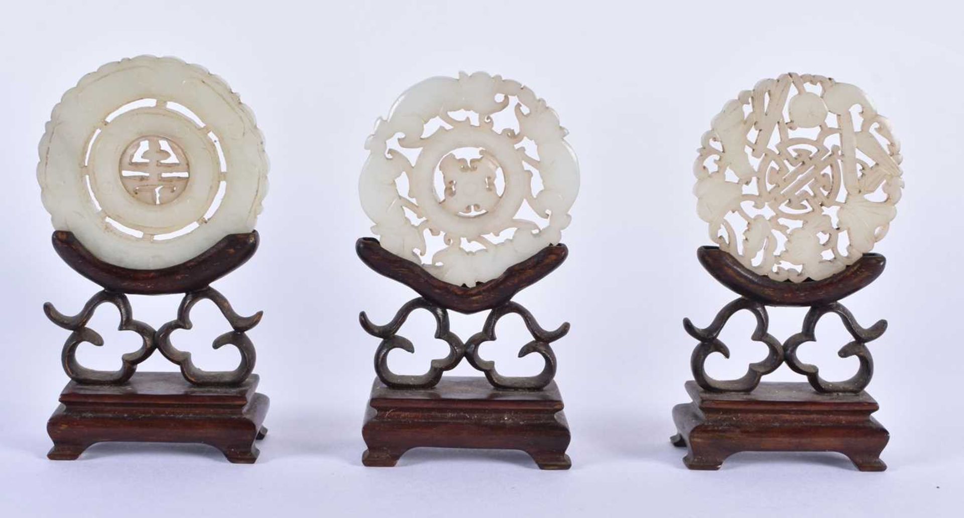 THREE 19TH CENTURY CHINESE GREEN JADE ROUNDELS Qing, in various forms. Jade 5 cm wide. (3)
