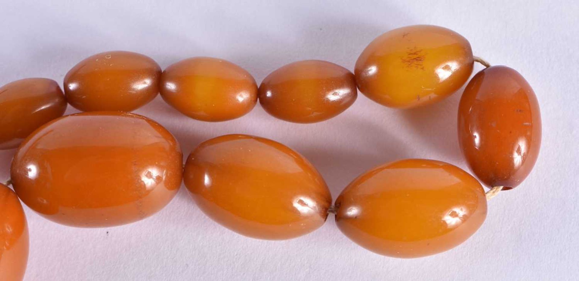 AN EARLY 20TH CENTURY CARVED BUTTERSCOTCH AMBER NECKLACE. 39 grams. 50 cm long, largest bead 2.75 cm - Image 2 of 4