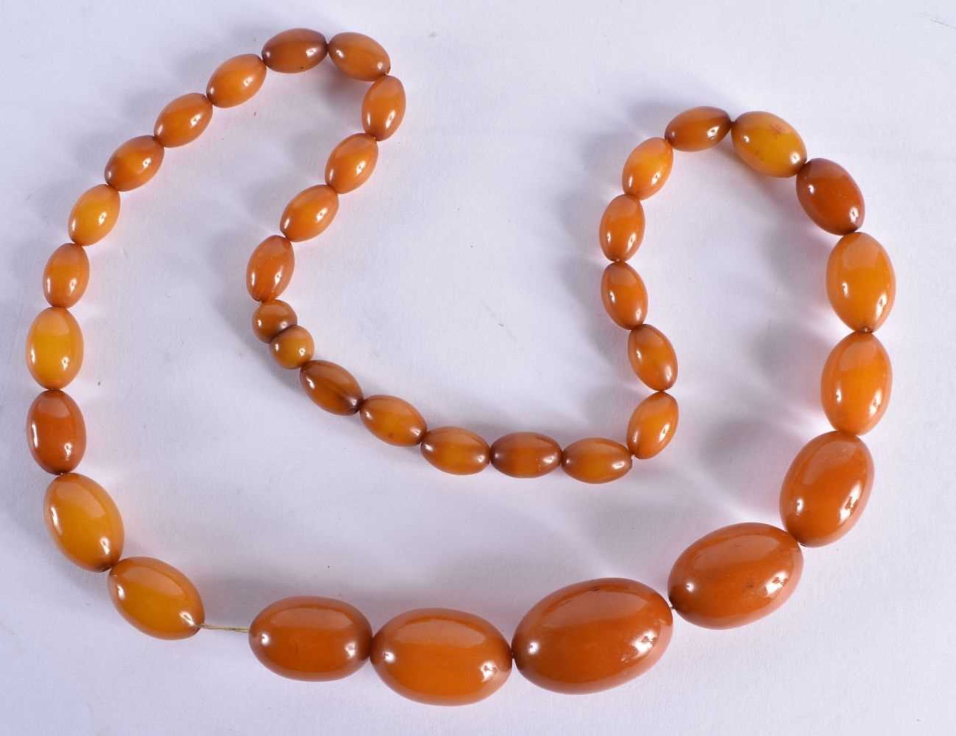 AN EARLY 20TH CENTURY CARVED BUTTERSCOTCH AMBER NECKLACE. 39 grams. 50 cm long, largest bead 2.75 cm