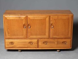 AN ERCOL WINDSOR MODEL 468 SIDEBOARD, in blond elm, the fascia with three blind panel cupboard doors