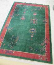 A CHINESE RUG, first half 20th century, the emerald field with floral sprays, vase and hanging