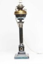 AN EDWARDIAN TABLE OIL LAMP, the reservoir raised on a Corinthian column, on stepped square base,