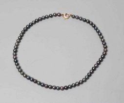 A SINGLE STRING OF BLACK CULTURED PEARLS, the circular clasp stamped 750 and point set with seven