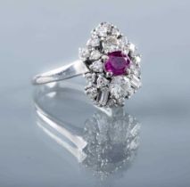 A MODERNIST RUBY AND DIAMOND RING, the central oval facet cut ruby claw set to an abstract border of
