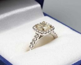 A DIAMOND CLUSTER RING, the cushion cut central stone of 1.03cts, claw set to a border of eighteen