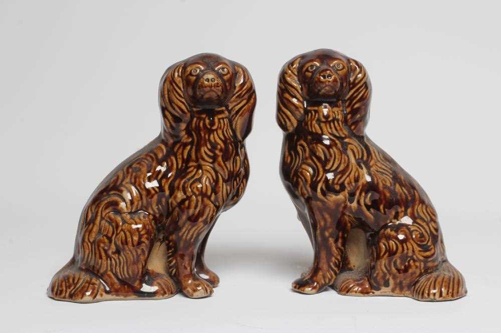 A PAIR OF EARLY VICTORIAN TREACLE GLAZED HEAVY STONEWARE SPANIELS modelled with a free standing fore