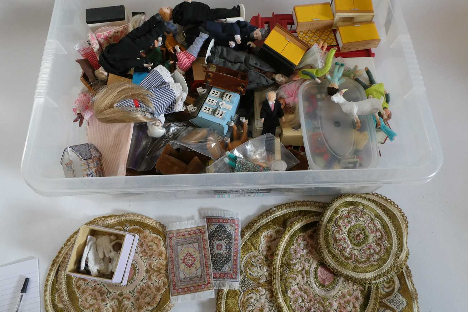 A box of dolls house furniture, dolls and accessories, including a large model telephone box, rugs