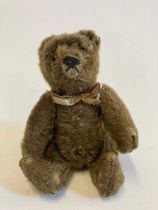 Small Steiff jointed bear, with glass eyes, brown plush, fabric bow and white metal ear button, 5