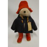 Paddington bear, with amber eyes, red felt hat, blue felt coat, red Dunlop boots and card label,
