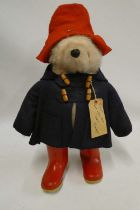 Paddington bear, with amber eyes, red felt hat, blue felt coat, red Dunlop boots and card label,