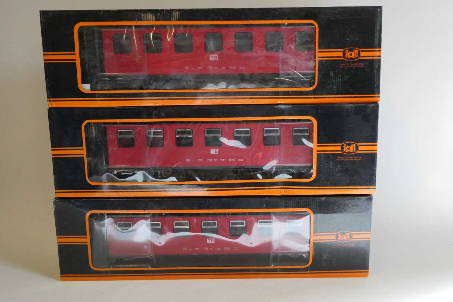 Three bogie coaches of German railway type finished in red, boxed, good to excellent