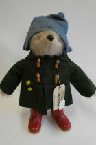 Paddington bear, with amber eyes, green felt coat, blue felt hat, red Dunlop boots, and card