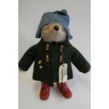 Paddington bear, with amber eyes, green felt coat, blue felt hat, red Dunlop boots, and card
