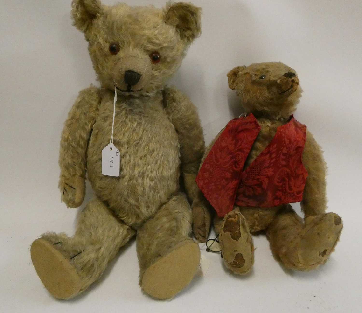 Two old straw filled teddies, comprising a 20" vintage English bear with shaven muzzle, amber eyes