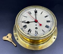 A vintage military bulkhead brass 8 day ships clock made by F.W. Elliot Ltd of Croydon, with slow/