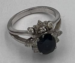 A 14 carat white gold ring set with central sapphire surrounded by diamonds. Size K. Weight 5gm.