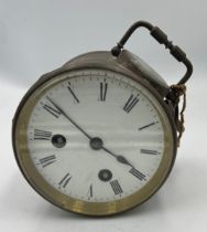 Circular brass cased clock with visible escapement and carrying handle.