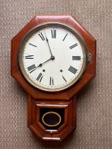 A mahogany wall clock with pendulum and key. Enamel face and Roman numerals.