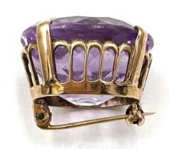 A yellow metal brooch set with amethyst. Approximate size 2.3cm x 2cm. Weight 10.1gm.