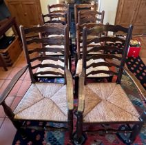 Eight oak ladder back dining chairs with rush seats to include two carvers.