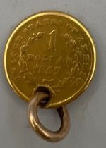A gold American one dollar coin. 1852. Drilled with holes to make a pendant.
