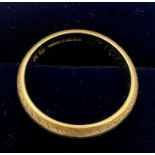 An 18 carat yellow gold wedding band with etched decoration. Size L/M. Weight 3.8gm.
