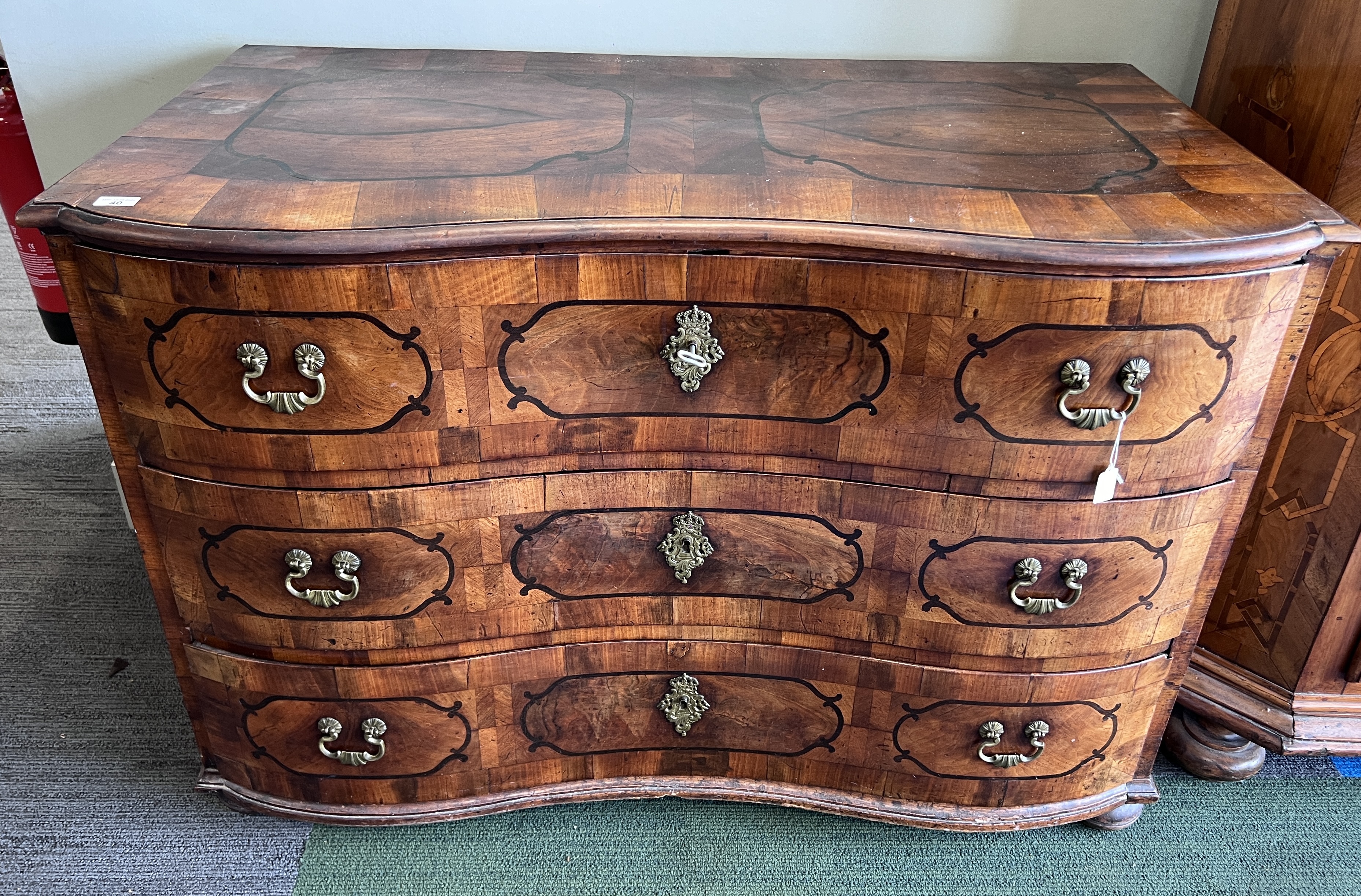 An 18thC Austrian parquetry inlaid serpentine fronted chest of three drawers with brass fittings, on