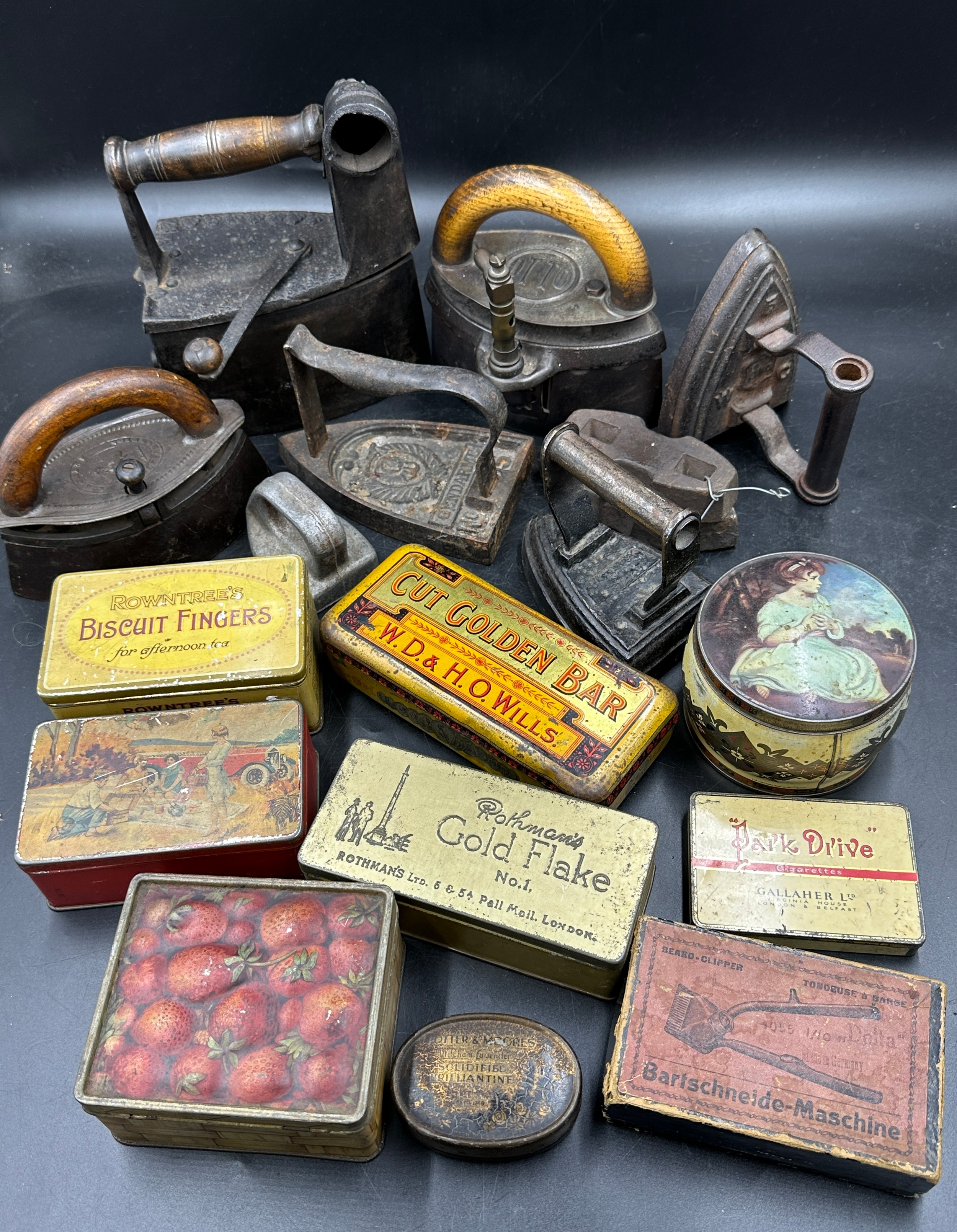 A collection of sad irons, CH Crane, Otto etc together with various tins to include Rowntree's