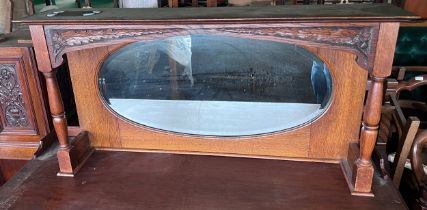 An oak framed mirror with shelf to top and carved decoration. 106cm w x 22cm d x 53 cm h.