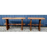 A pair of oak trestle type benches/stools with rectangular tops on shaped ends joined by stretchers,