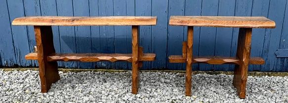 A pair of oak trestle type benches/stools with rectangular tops on shaped ends joined by stretchers,