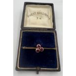 A nine carat gold bar brooch set with three pink stones in a presentation box. Weight 2.2gm.
