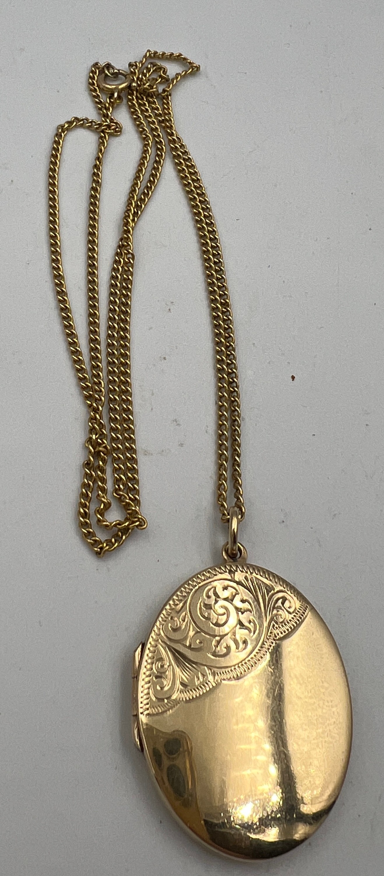 A nine carat gold oval locket and chain. Chain 54cm long. Locket 3cm x 2.5cm approximately. Weight