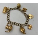 A nine carat gold chain bracelet with heart shaped padlock clasp and six charms, three marked 9