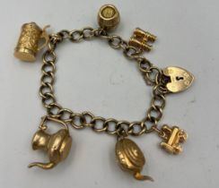 A nine carat gold chain bracelet with heart shaped padlock clasp and six charms, three marked 9