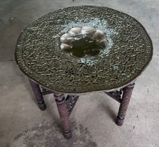 A brass topped tiffin table with carved folding base. 75cm d.