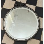 A heavy circular metal bevelled mirror with bowed ribbon decoration to the top. 48.5cm d, 56cm h