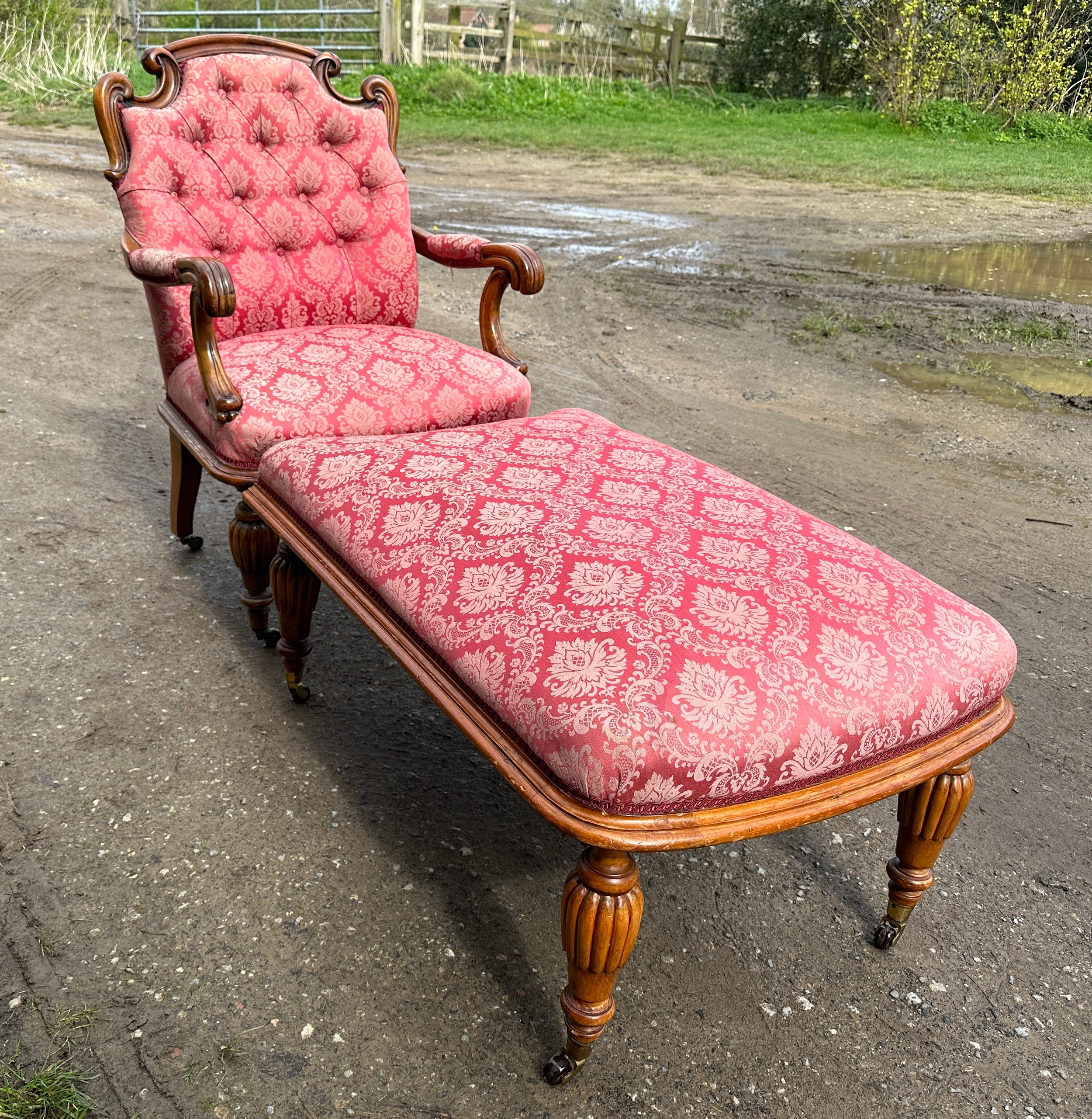 An upholstered armchair with turned reeded legs and brass castors together with abutting footstool