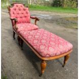 An upholstered armchair with turned reeded legs and brass castors together with abutting footstool