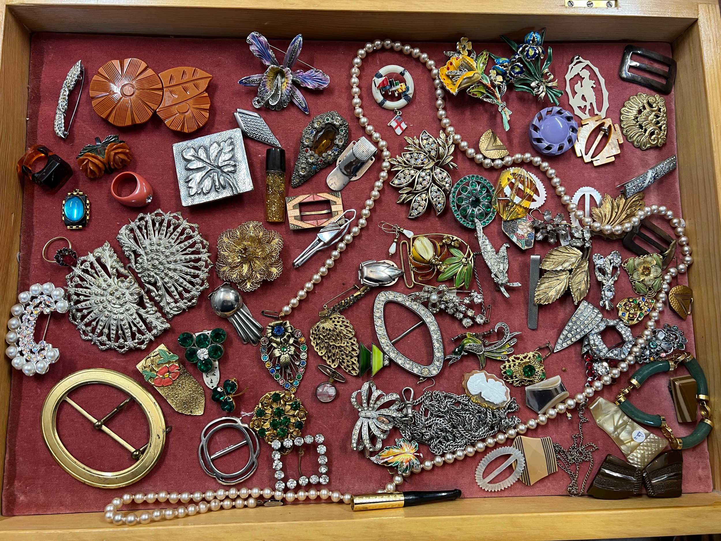 A pine framed table top display case and contents comprising vintage brooches, dress clips, belt