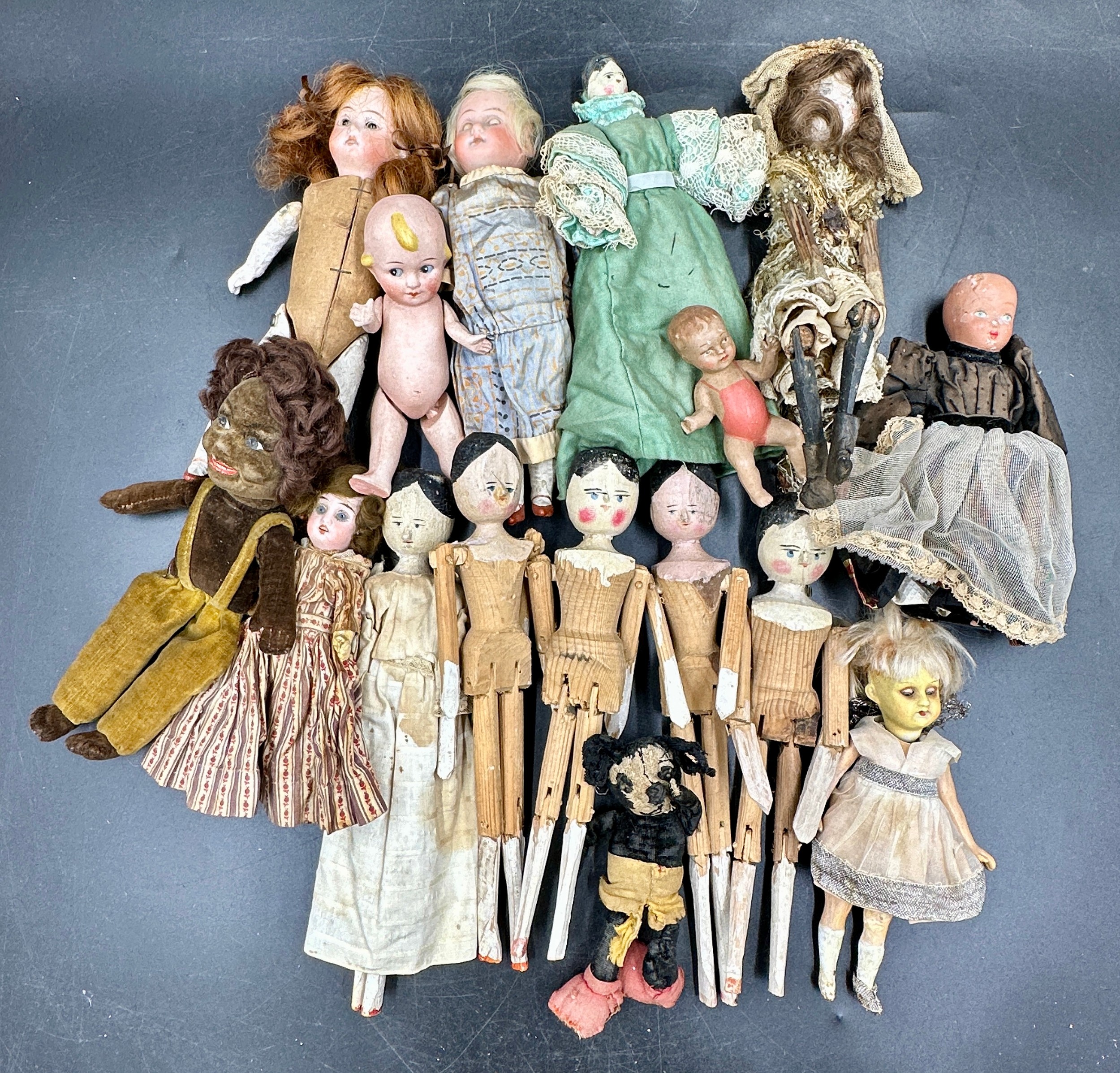 A collection of small dolls to include seven folk art style wooden peg dolls, 15cm l, six with